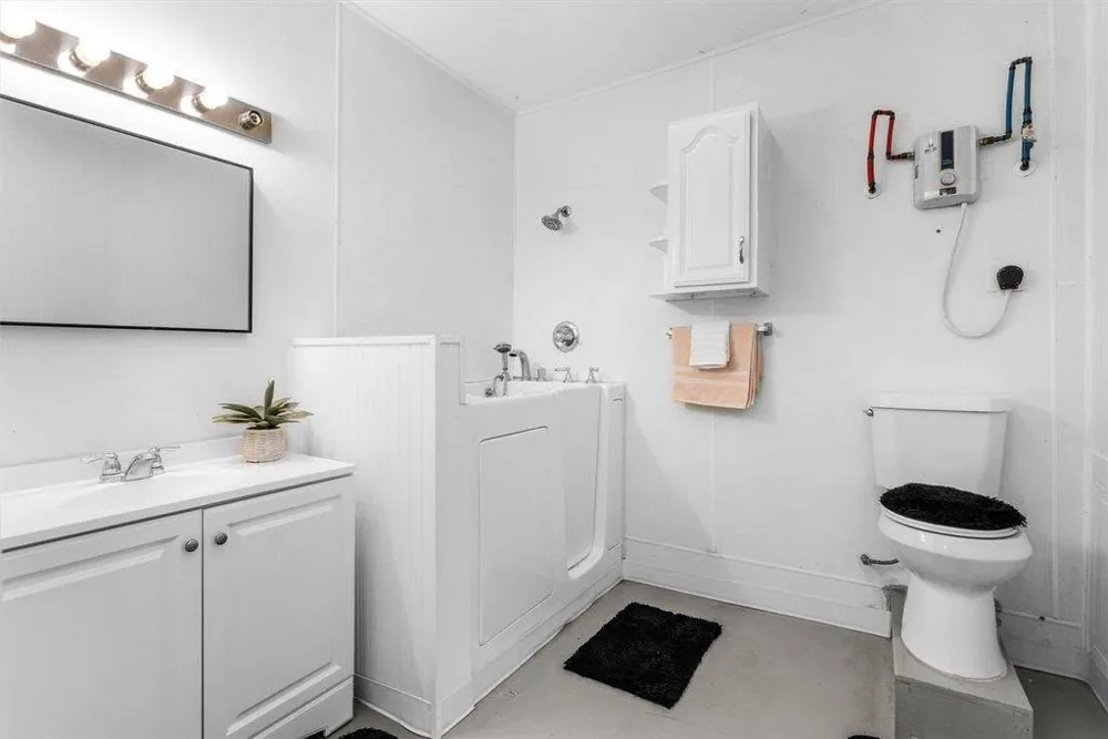 Walk-in tub installation alongside a vanity and toilet in a white bathroom