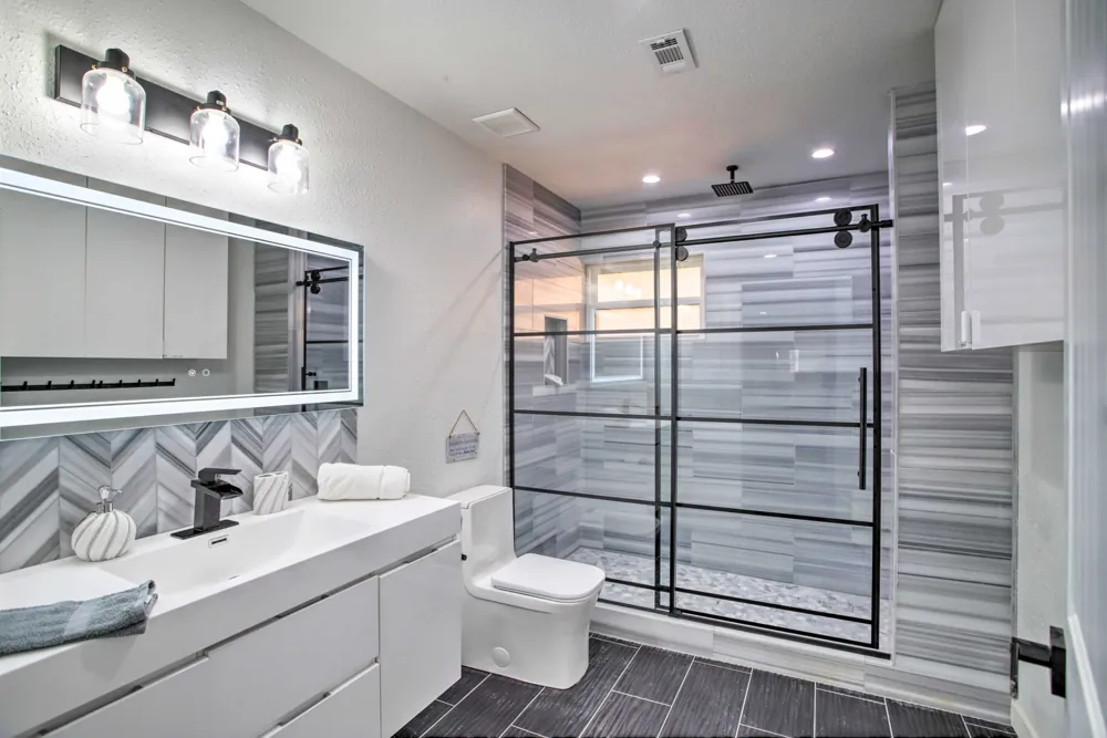 Bathroom with a double vanity, patterned backsplash and a glass walk-in shower