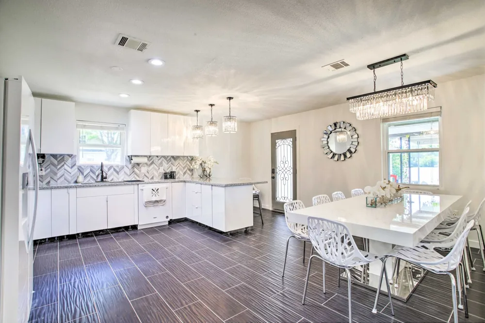White kitchen with an island opening into a dining room with dark flooring